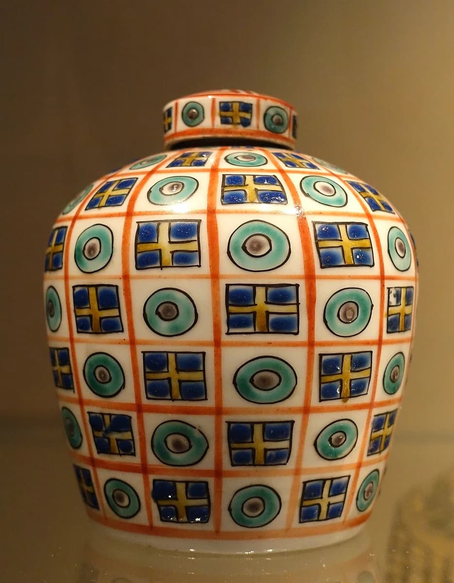 A patterned Japanese tea caddy displayed in warm gallery light.